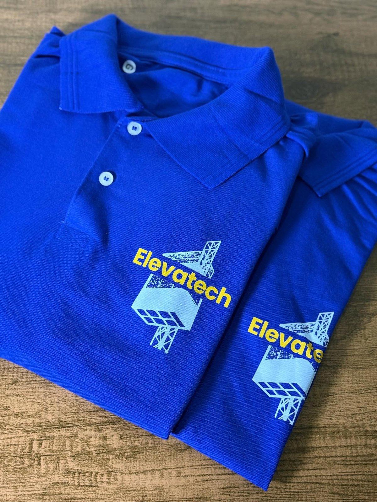 Camisas polo azul royal com marca da Elevatech aplicada, produzidas pela Aplicaê Uniformes
